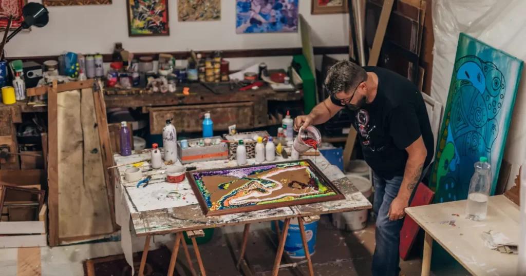Artist in studio creating painting and he is displaying divine feminine energy (creativity)